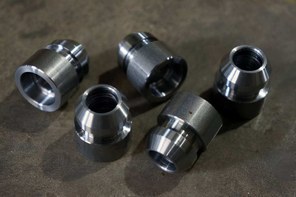 Identical Swiss turned machined parts displayed on the floor.