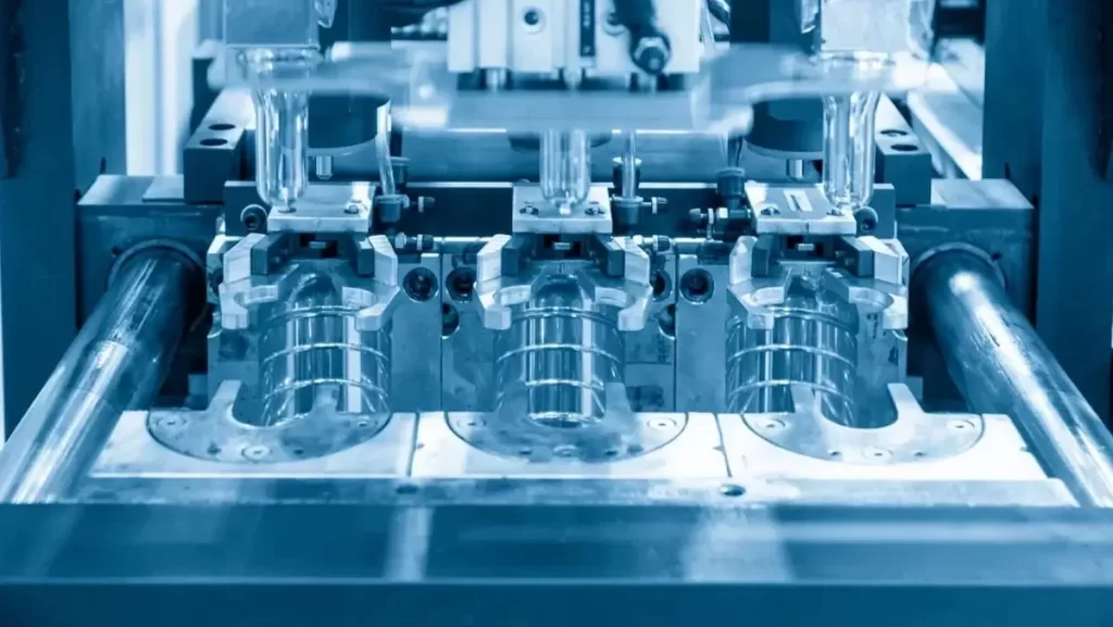 A close-up of clear plastic bottles being formed within a machine, highlighting the molding process.