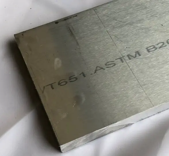 A close-up of a thick plate of Aluminum 6061-T6 on a white surface