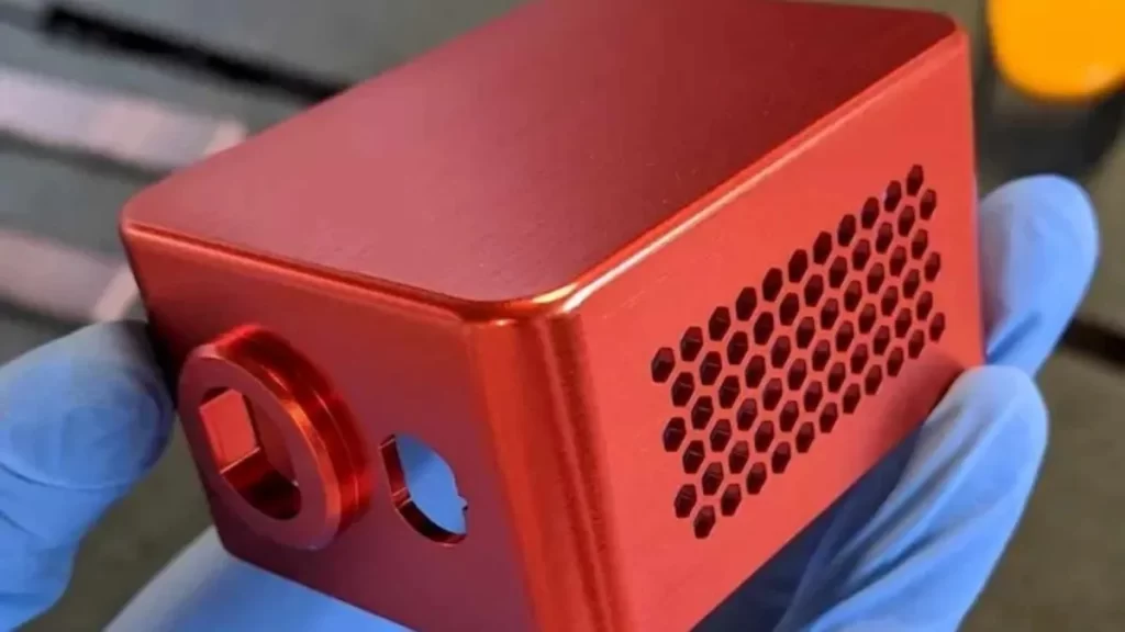 An image showing a person holding a red anodized electronics enclosure. 