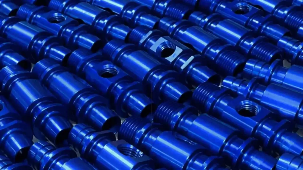 An image showing neatly arranged anodized parts with a sleek dark blue finish.