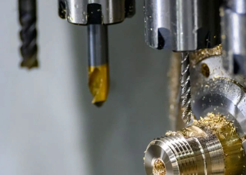 CNC drill bits creating holes in a metal workpiece with chips