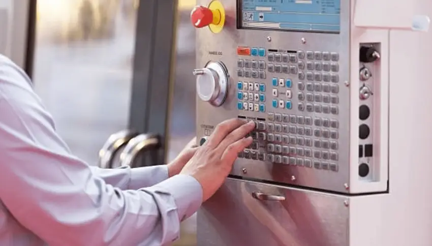 Operator hands programming the CNC machine control panel 