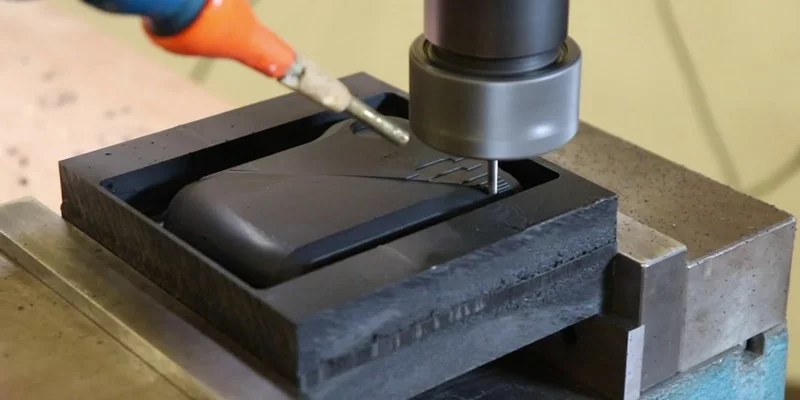 CNC milling machine cutting a mold from black material.