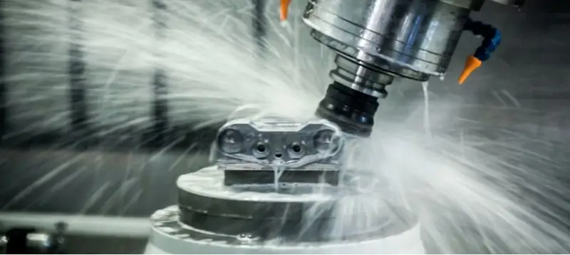 CNC machine cutting metal with coolant spray.