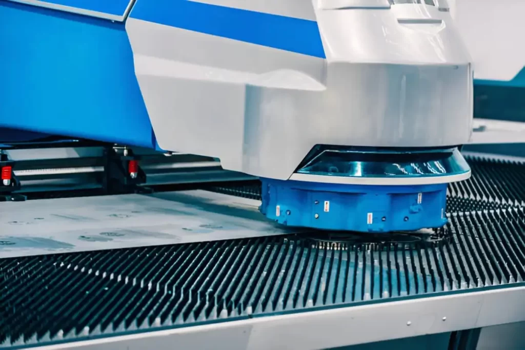 Image shows a CNC turret punching machine working on sheet metal.
