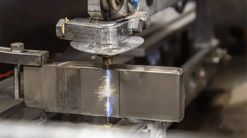 The image displaying an EDM machine operates with sparks eroding the workpiece.