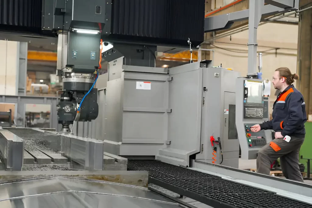 An operator controlling and watching the milling process on a gantry machine.