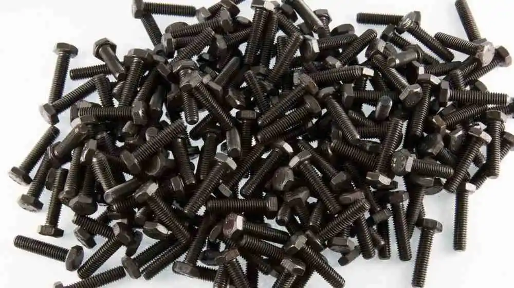 A close-up of a large pile of black hex head bolts.