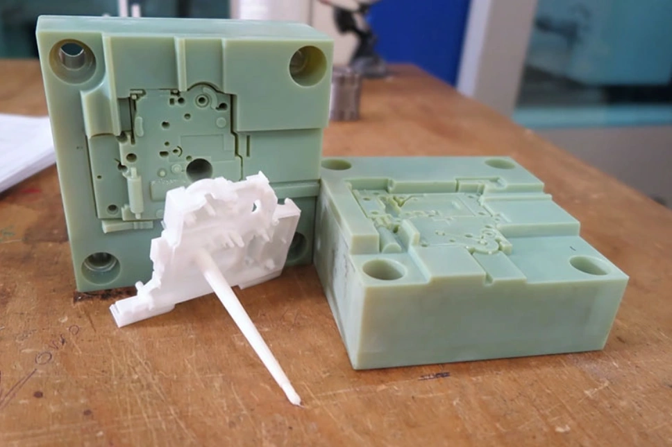 3D printed injection mold tooling with white prototype part indicating affordable rapid prototyping
