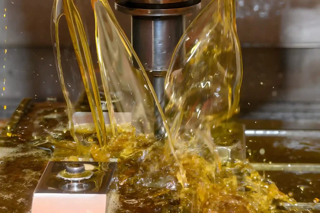 The image shows a CNC machine delivering oil-based coolant directly onto the cutting zone through flexible nozzles. 